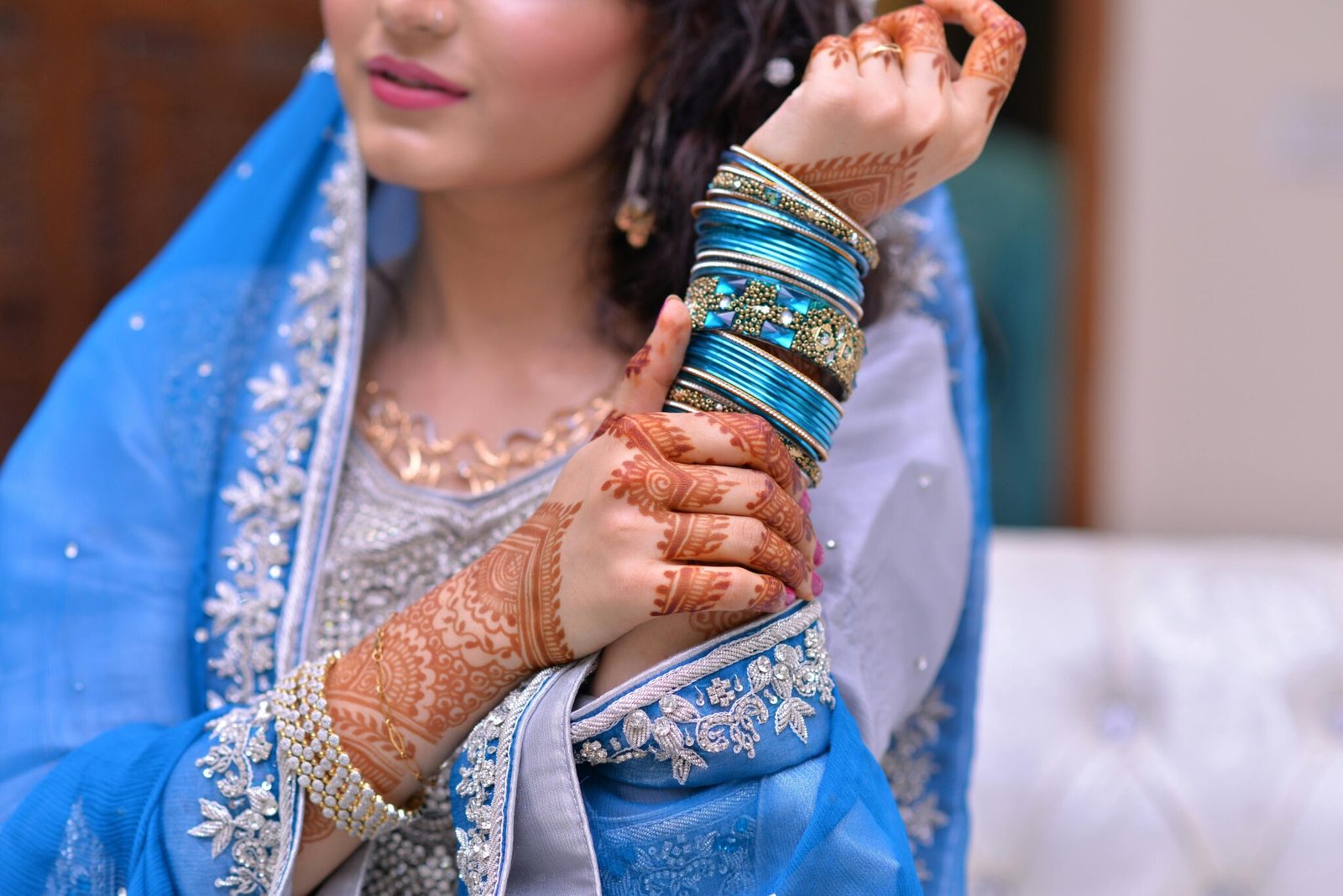 A bride showcases intricate henna designs and vibrant jewelry in traditional attire.